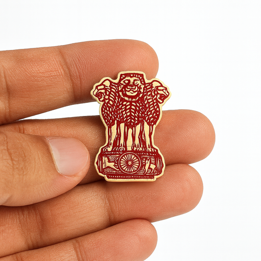 Small red and gold emblem held between fingers on a white background