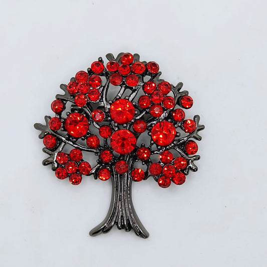 A brooch designed as a tree of life with a gunmetal finish and red crystal embellishments.