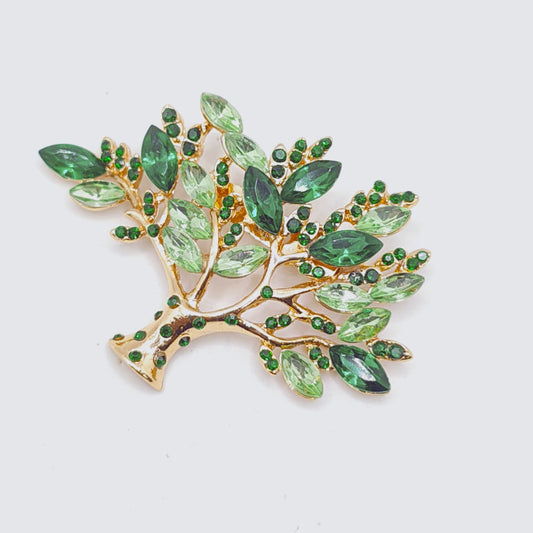 Jewelry brooch with green gemstones on a white background