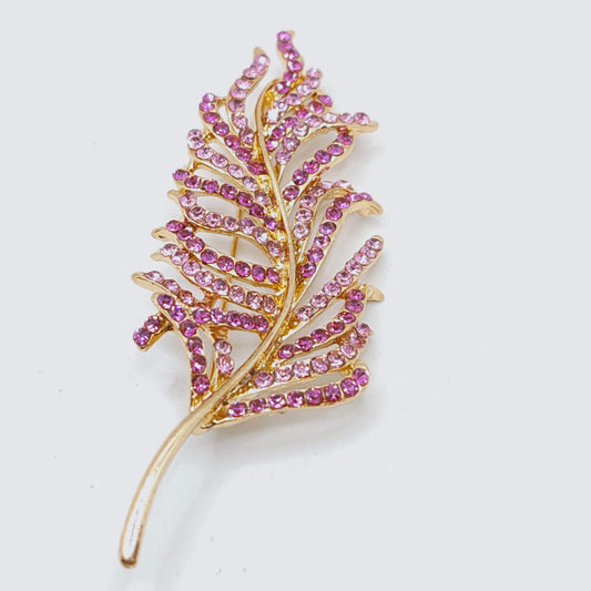 Gold and pink leaf-shaped brooch on a white background