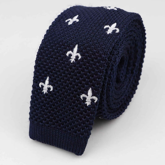 Navy knitted tie with white fleur-de-lis patterns on a light gray background