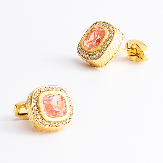 Gold cufflinks with pink gemstones on a white background