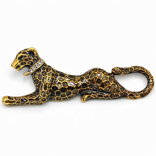 Gold and black panther-shaped brooch with gemstones on a white background