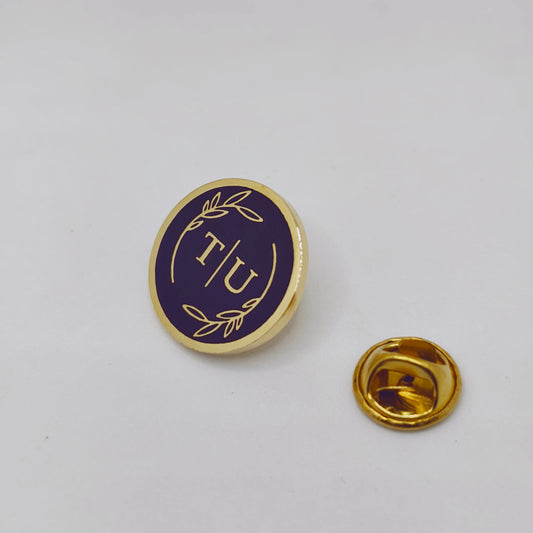 Gold and purple pin with 'IU' on a white background