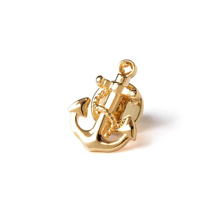 A gold-colored brass lapel pin in the shape of an anchor with a rope.