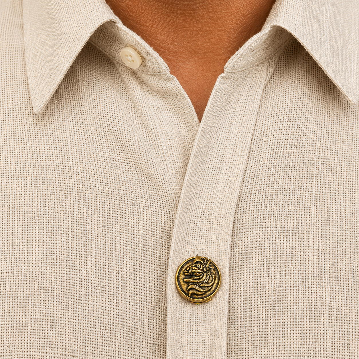 Close-up of a beige shirt with a decorative button featuring a dragon design.