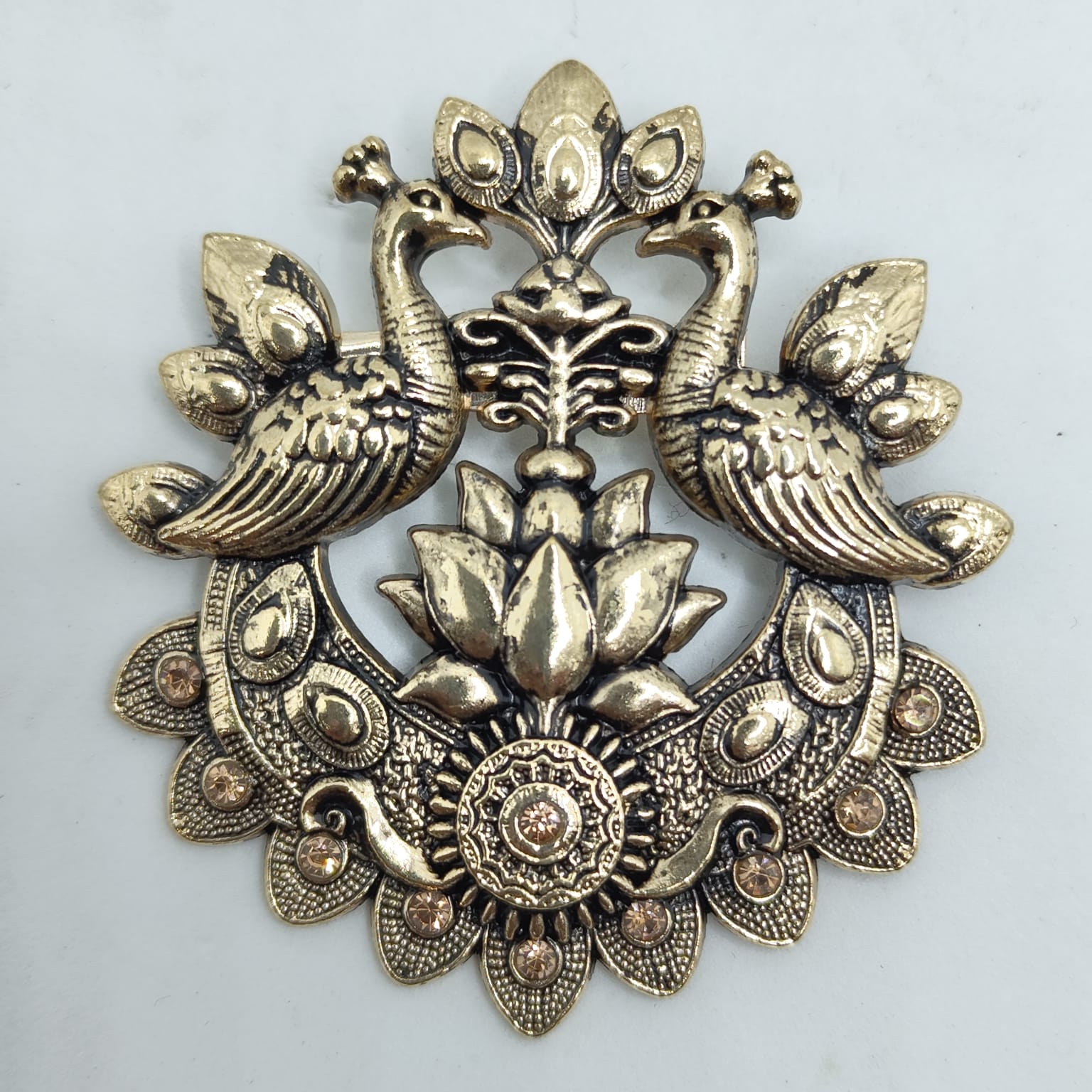 Decorative brass peacock design on a light gray background