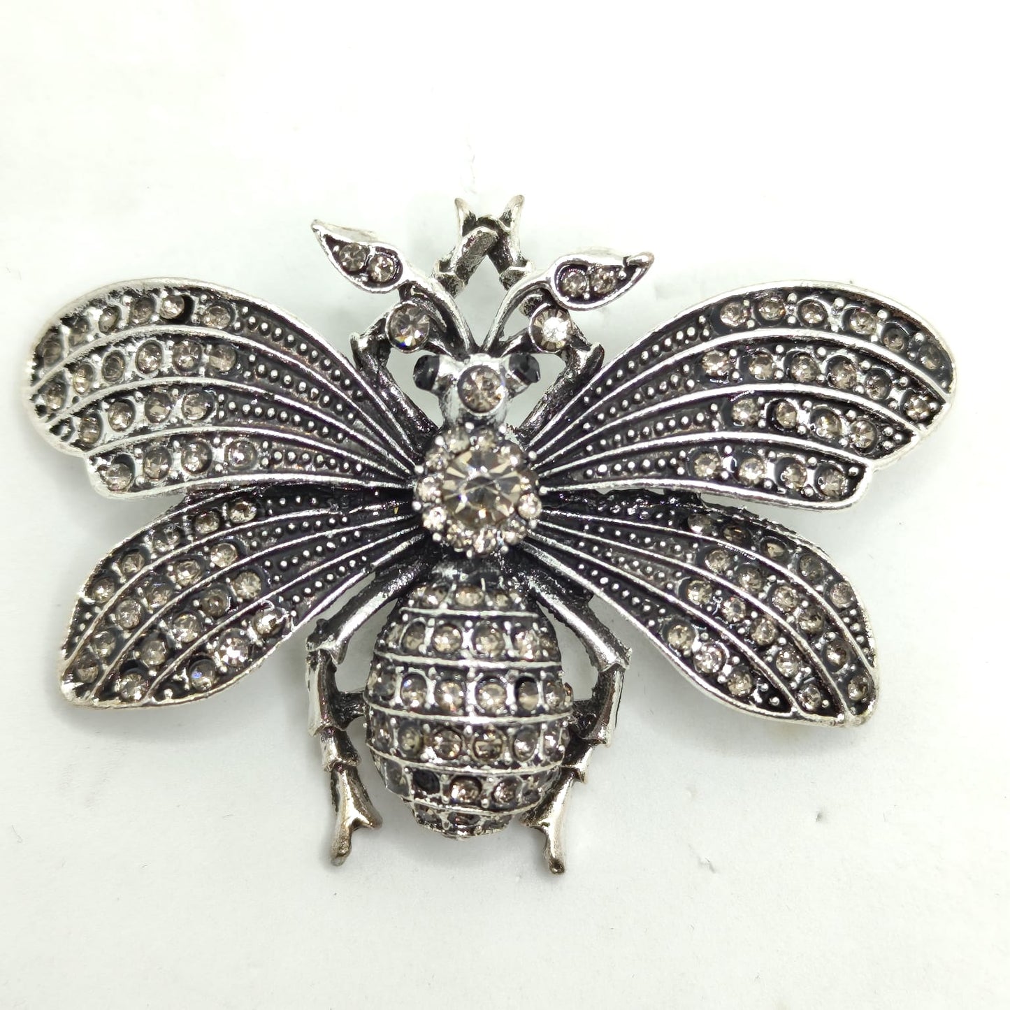 Silver bee-shaped brooch with rhinestones on a white background