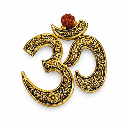 Decorative gold and black Om symbol with a red stone on a white background