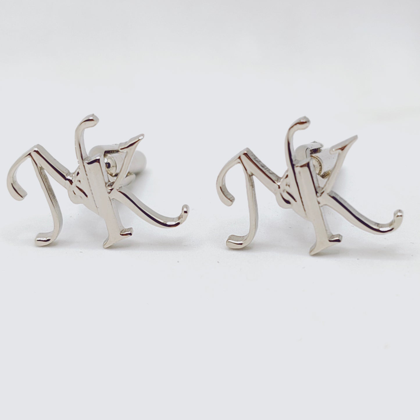 Silver 'NK' letter cufflinks on a white background