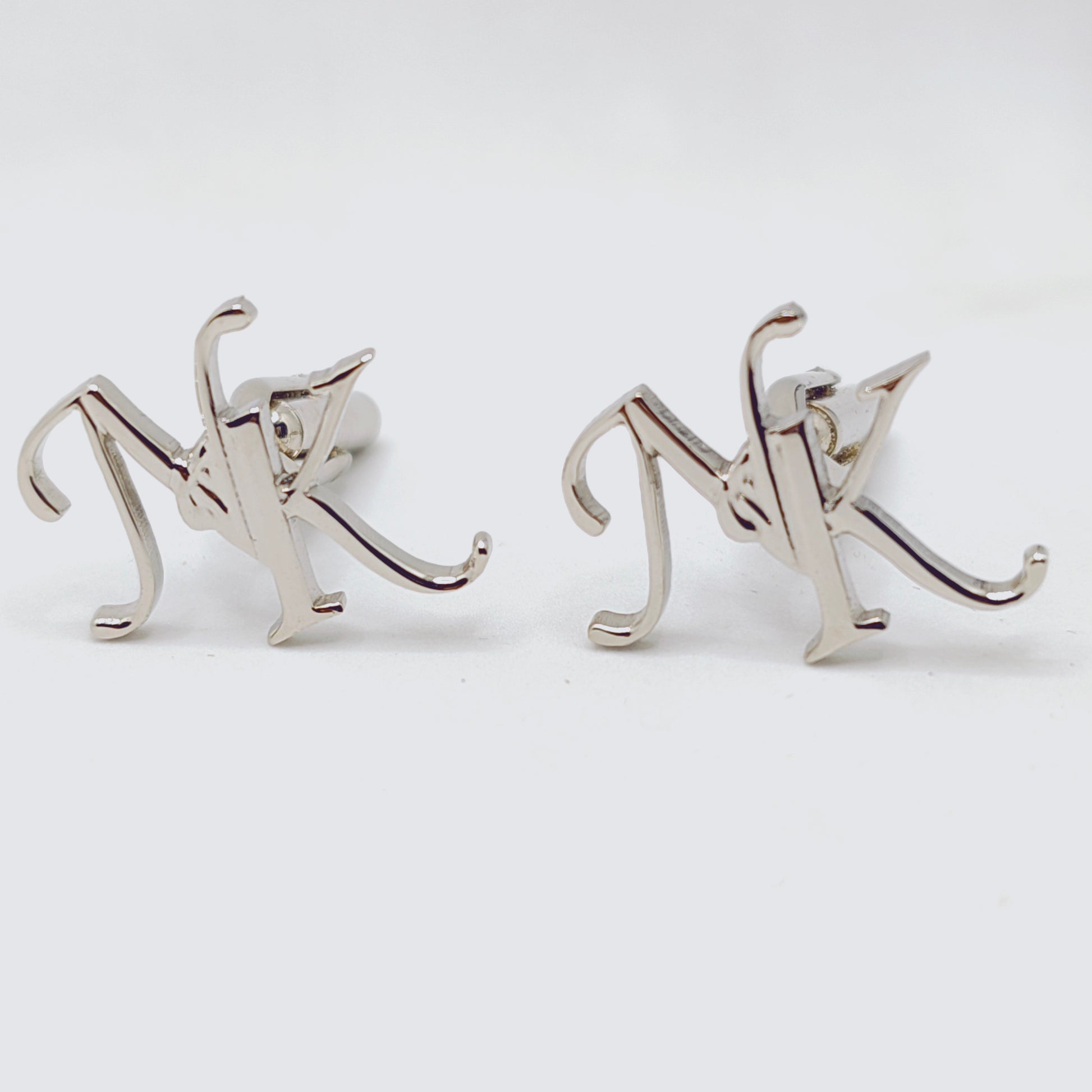 Silver 'NK' letter cufflinks on a white background